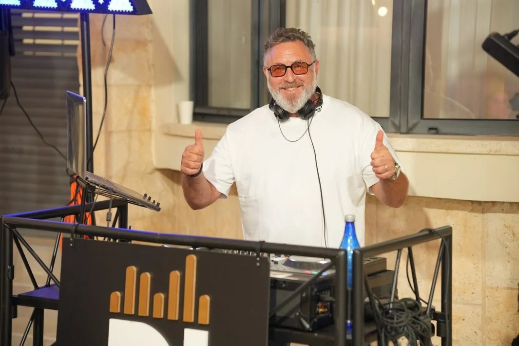 Aviad Leder performing live at a DJ booth with professional mixing equipment.